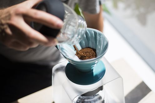 Pouring ground coffee into a V60 dripper.